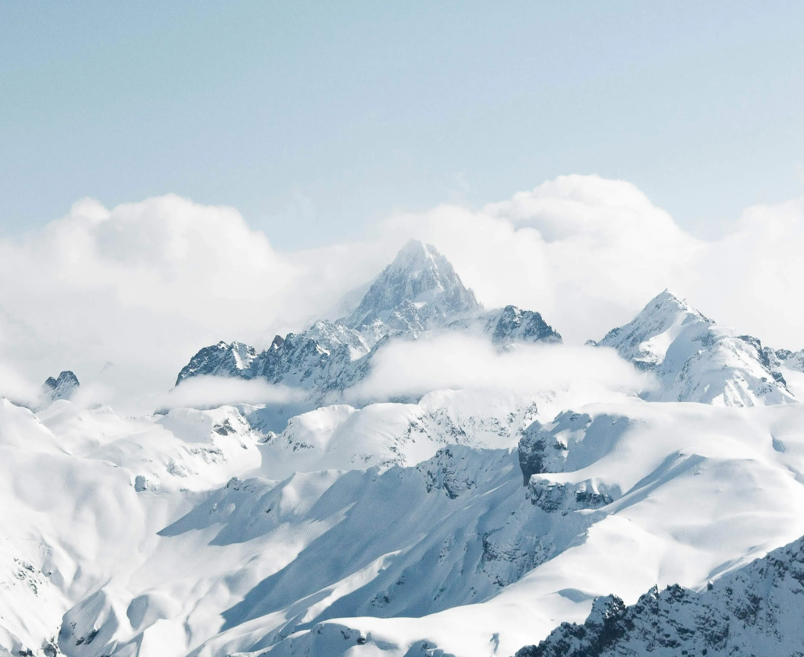 Snowy mountain peaks with clouds.